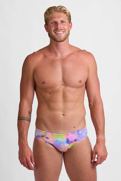 Male models wearing the Men's Brolyn Brief Swimsuit in the Brightlight print, standing in front of a grey background, shown from front view. 