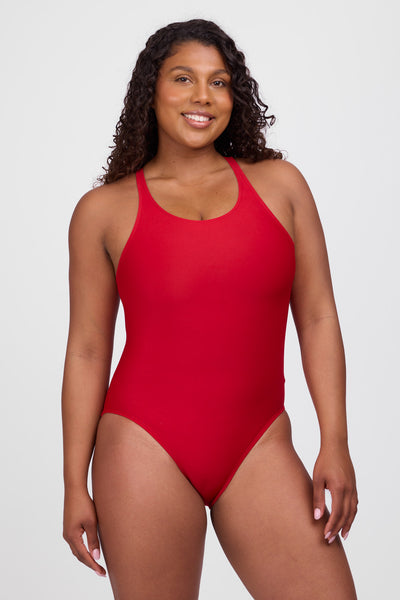 Female model wearing the Women’s Nancy One Piece Swimsuit in the Red solid, standing in front of a grey background, shown from front view. 