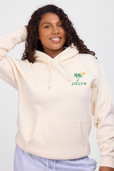 Female model wearing the Womens Raine Hoodie in the Vibin Bone solid, standing in front of a grey background, shown from the front view
