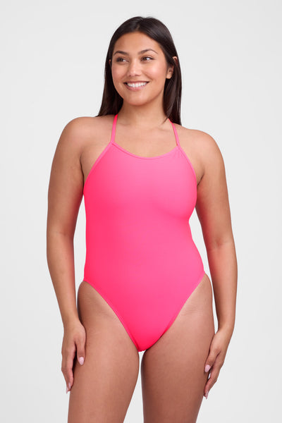Female model wearing the Women's Brandon One Piece Swimsuit in the Hot Pink solid, standing in front of a grey background, shown from front view. 