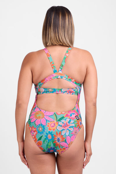 Female model wearing the Women's Caroline One Piece in the Pandora print, standing in front of a grey background, shown from back view. 