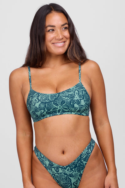 
Female model wearing the Women’s Delphine Bikini Top in the Sumba print, standing in front of a grey background,  shown from the front view
