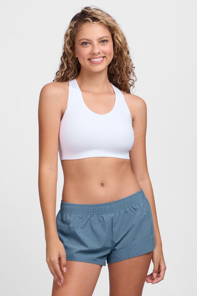 Female model wearing the Women’s Bennie Short in the Midnight Blue solid, standing in front of a grey background, shown from front view. 