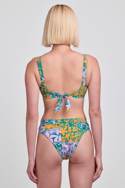 
Female model wearing the Women's Alanna Bikini Bottom in the Echo print, standing in front of a grey background, shown from back view.  