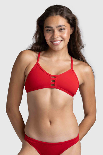 Female model wearing a Women's Tomcat Bikini Top in the Red solid, standing in front of a grey background, shown from front view.