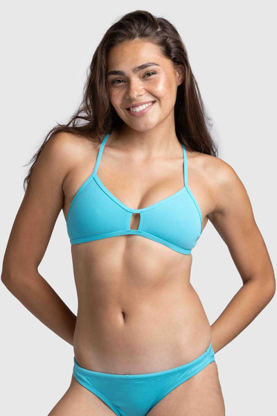 Female model wearing the Women's Vent Bikini Top in the Hawaii Blue solid, standing in front of a grey background, shown from front view. 