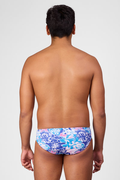 Male model wearing the Men's Brolyn Swim Brief in the Maui print, standing in front of a grey background shown from the back view

