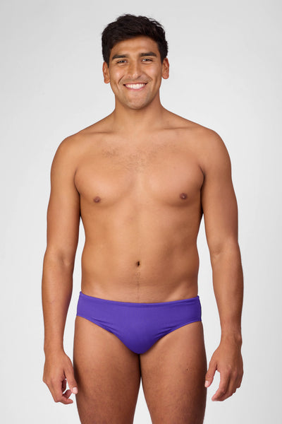 Male model wearing the Men's Brolyn Swim Brief in the Purple solid, standing in front of a grey background shown from the front view