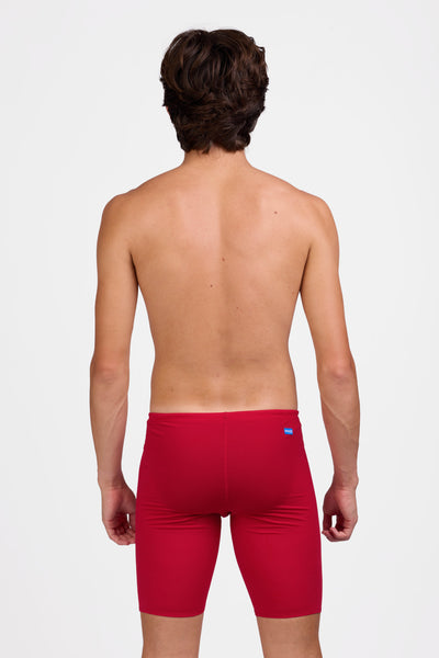 Male model wearing the Men's BROLYN Jammer in the Red solid, standing in front of a grey background shown from the back view