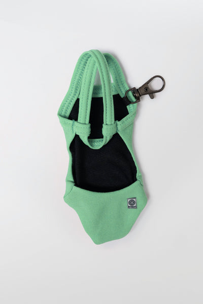Flat lay image of Mini Me Brandon Keychain in the Green Apple Solid, in front of a grey background, shown from the back view
