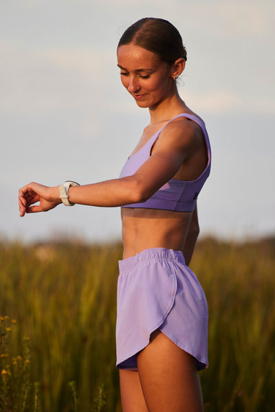 Female model wearing the Women's Lizzie Short in the Lilac Haze solid, standing in front of a green background shown from the side view 

|| Size S, Hip 36"