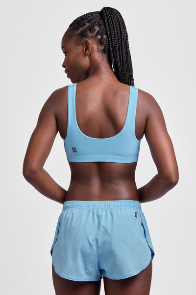 Female model wearing the Women's Lizzie Split Short in the Sky Wave solid, standing in front of a grey background, shown from the back view.
