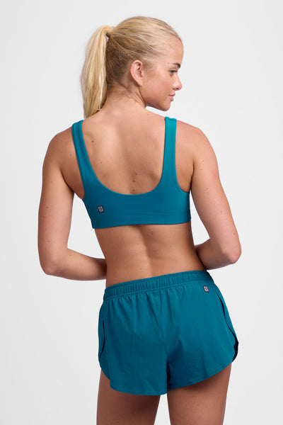 Female model wearing the Women's Lizzie Split Short in the Space solid, standing in front of a grey background, shown from the back view.