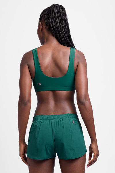 Female model wearing the Women's Rory Short in the Basil solid, standing in front of a grey background, shown from the back view.