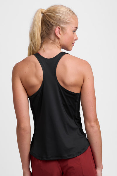 Female model wearing the Women’s Monti Run Singlet in the Basil solid, standing in front of a grey background, shown from back view. 