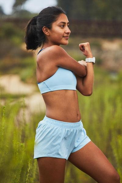 Female model wearing the Women's Rory Short in the Sky Wave solid, standing in front of a green background, shown from the side view.