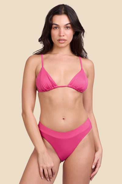 Female model wearing the Women's Alanna Bikini Bottom in the Berry solid, standing in front of a yellow background shown from the front view

|| Size S, Hips 34"  
