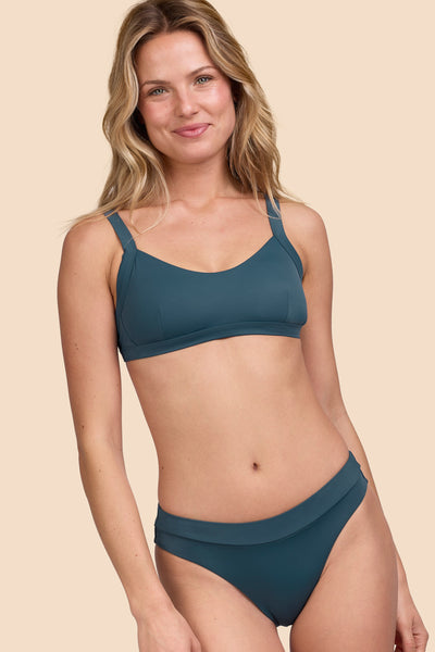 Female model wearing the Women's Alanna Bikini Bottom in the Underwater solid, standing in front of a yellow background shown from the front view

|| Size S, Hip 36"  