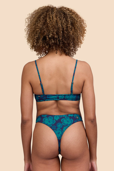 Female model wearing the Women's Ava Bikini Bottom in the Moon Flower print, standing in front of a yellow background, shown from the back view

|| Size S, Hip 36"
