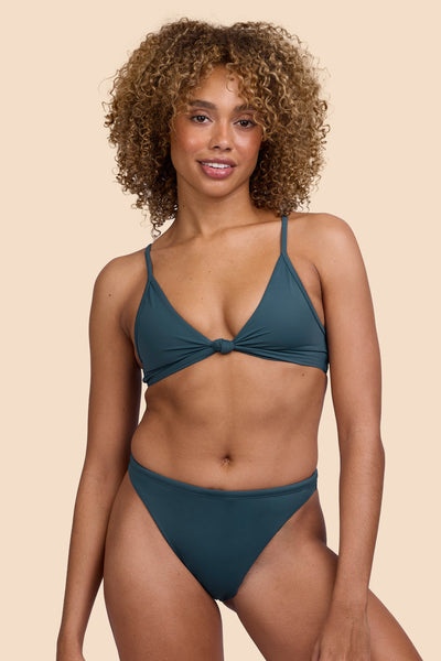 Female model wearing the Women's Ava Bikini Bottom in the Underwater solid, standing in front of a yellow background shown from the front view

|| Size S, Hip 36"  