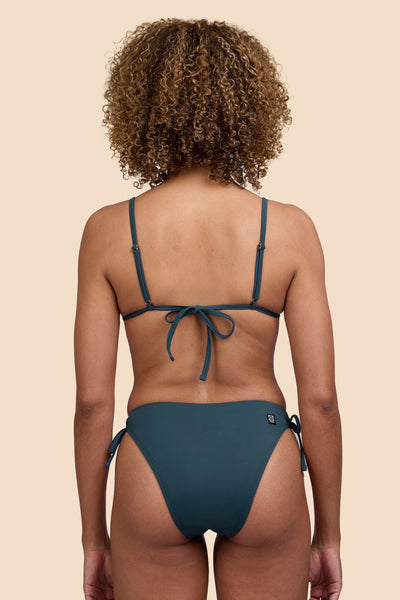 Female model wearing the Women's Bella Bikini Bottom in the Underwater solid, standing in front of a yellow background shown from the back view

|| Size S, Hip 36"  