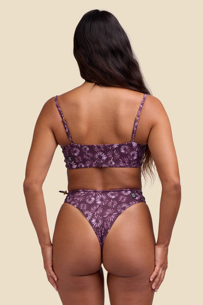 Female model wearing the Women's Ciara Bikini Bottom in the Bondi Blossom print, standing in front of a yellow background shown from the back view

|| Size S, Hips 35"  