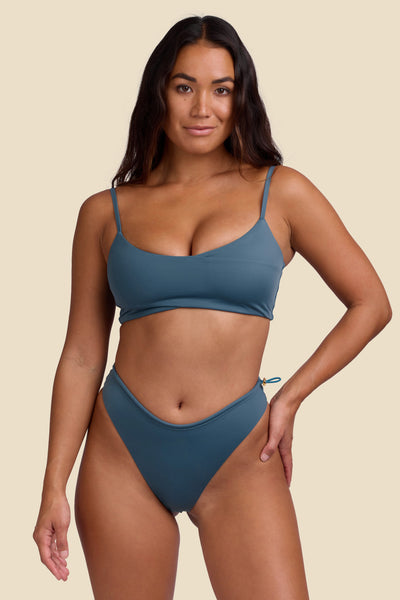 Female model wearing the Women's Ciara Bikini Bottom in the Horizon solid, standing in front of a yellow background shown from the front view

|| Size S, Hips 35"  