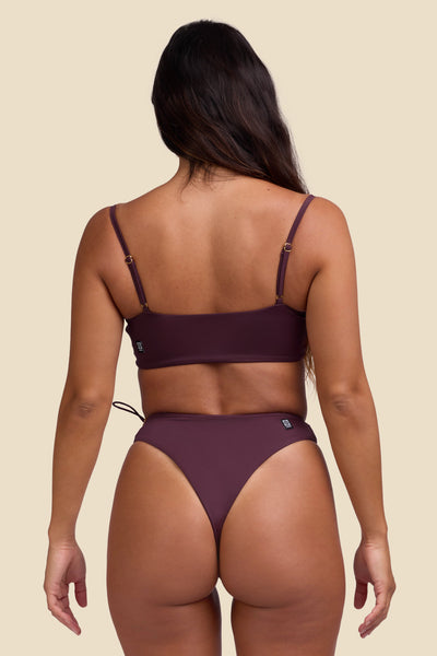 Female model wearing the Women's Ciara Bikini Bottom in the Sangria solid, standing in front of a yellow background shown from the back view

|| Size S, Hips 35"  