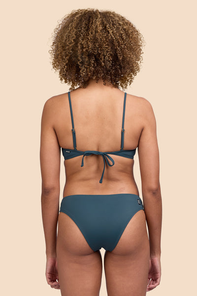 Female model wearing the Women's Gina Bikini Bottom in the Underwater solid, standing in front of a yellow background shown from the back view

|| Size S, Hip 36"  