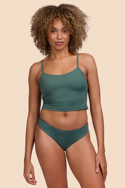 Female model wearing the Womens Gina Bikini Bottom in the Zucchini solid, standing in front of a yellow background shown from the front view

|| Size S, Hip 36"  
