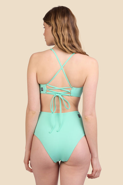 Female model wearing the Women's Janna Bikini Bottom in the Mint Tulip solid, standing in front of a yellow background shown from the back view

|| Size S, Hips 37"  
