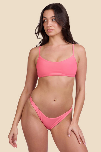 Female model wearing the Women's Kelia Bikini Bottom in the Tea Rose Ribbed solid, standing in front of a yellow background shown from the front view

|| Size S, Hips 34"  