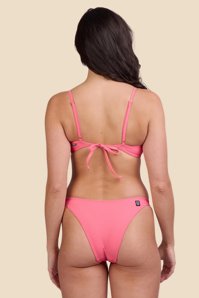 Female model wearing the Women's Kelia Bikini Bottom in the Tea Rose Ribbed solid, standing in front of a yellow background shown from the back view

|| Size S, Hips 34"  