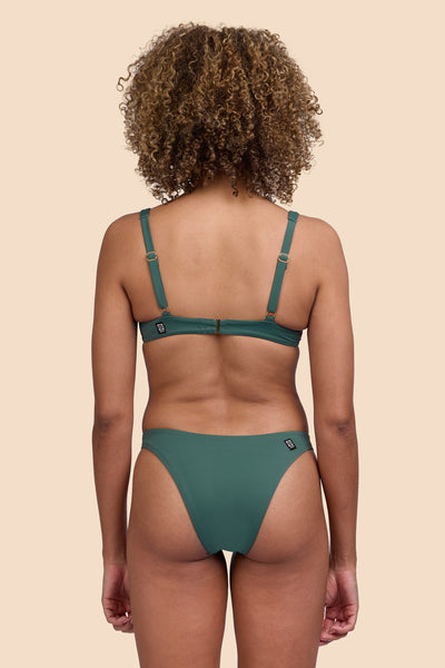 Female model wearing the Womens Kelia Bikini Bottom in the Zucchini solid, standing in front of a yellow background shown from the back view

|| Size S, Hip 36"  