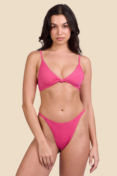 Female model wearing the Women's Odessa Bikini Bottom in the Berry solid, standing in front of a yellow background shown from the front view

|| Size S, Hips 34"  
