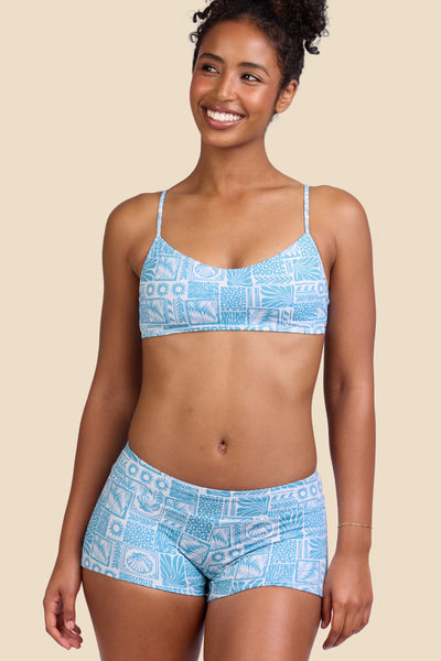 Female model wearing the Women's Piha Surf Short in the Swell print, standing in front of a yellow background shown from the side view

|| Size S, Hips 37" 
