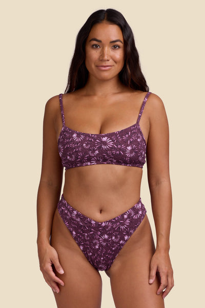 Female model wearing the Women's Sirena Bikini Bottom in the Bondi Blossom print, standing in front of a yellow background shown from the front view

|| Size S, Hips 35"  