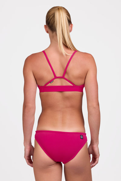 Female model wearing the Women's Andy Bikini Bottom in the Dragon Fruit solid, standing in front of a grey background shown from the back view

|| Size S, Hips 37"