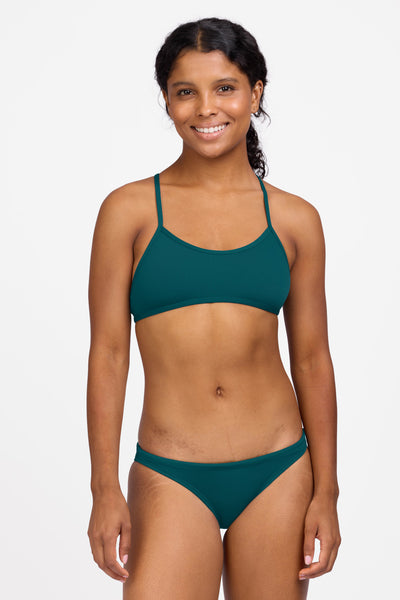 Female model wearing the Women's Europe Bikini Bottom in the Peacock solid, standing in front of a grey background shown from the front view

|| Size S, Hips 36.5"