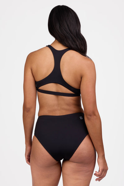 Female model wearing the Women's Sandra Bikini Bottom in the Black solid, standing in front of a grey background shown from the back view


|| Size M, Hips 40"