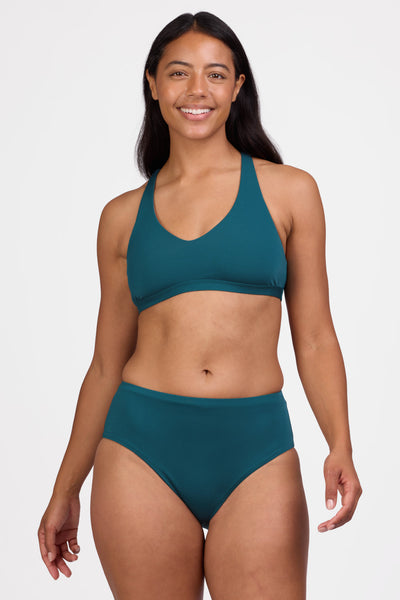 Female model wearing the Women's Sandra Bikini Bottom in the Peacock solid, standing in front of a grey background shown from the front view


|| Size M, Hips 40"