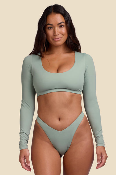 Female model wearing the Women's Avalon Rashguard in the Algae solid, standing in front of a yellow background shown front the front view

|| Size S, Bust 34"  