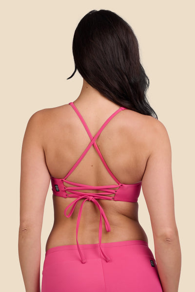 Female model wearing the Women's Blake Bikini Top in the Berry solid, standing in front of a yellow background shown from the back view

|| Size M, Bust 32"  
