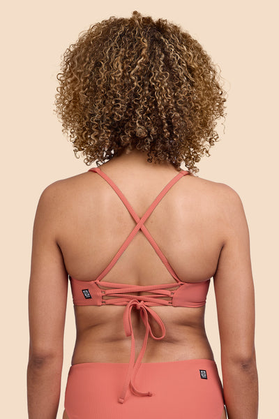 Female model wearing the Women's Blake Bikini Top in the Serrano Ribbed solid, standing in front of a yellow background, shown from the back view

|| Size S, Bust 32.5" 