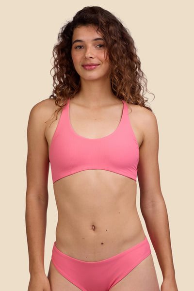 Female model wearing the Women's Blake Bikini Top in the Tea Rose Ribbed solid, standing in front of a yellow background shown from the front view

|| Size S, Bust 35.5"  