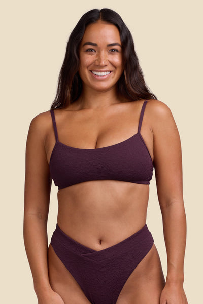 Female model wearing the Women's Delphine Bikini Top in the Sangria solid, standing in front of a yellow background shown from the front view

|| Size S, Bust 34"  