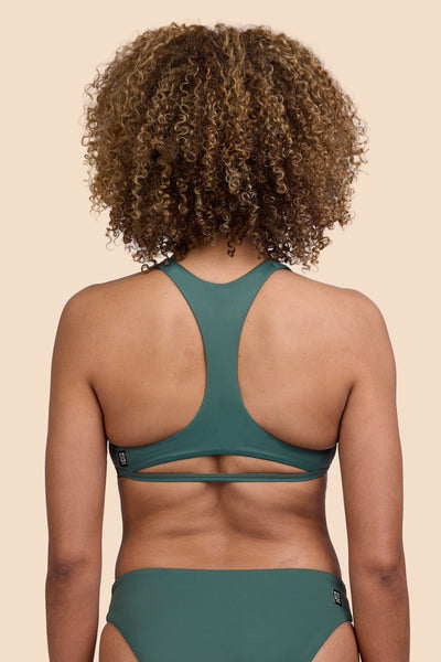 Female model wearing the Womens Doris Bikini Top in the Zucchini solid, standing in front of a yellow background shown from the back view

|| Size S, Bust 32.5"  