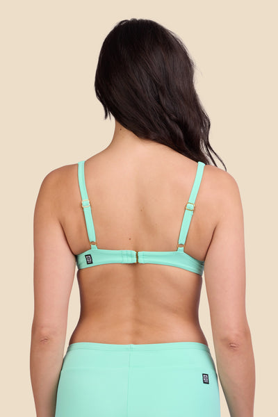Female model wearing the Women's Hadley Bikini Top in the Mint Tulip solid, standing in front of a yellow background shown from the back view

|| Size M, Bust 32"  
