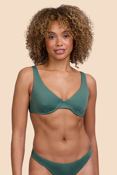 Female model wearing the Womens Hadley Bikini Top in the Zucchini solid, standing in front of a yellow background shown from the front view

|| Size S, Bust 32.5"  