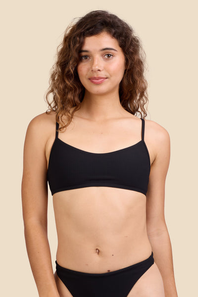 Female model wearing the Women's Hikari Bikini Top in the Black Ribbed solid, standing in front of a yellow background shown from the front view

|| Size S, Bust 35.5"  